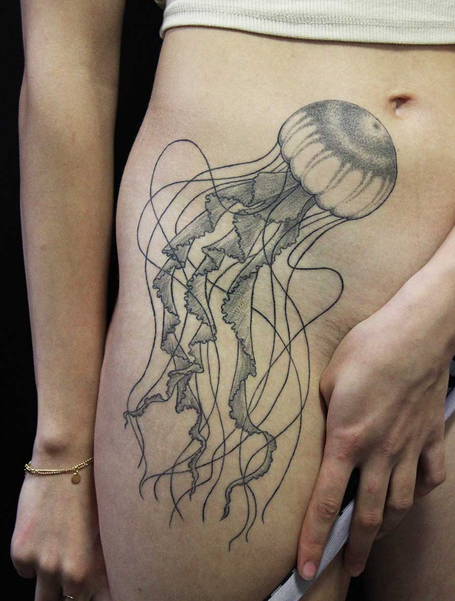 la méduse tatouée en lignes noires et ombrages au point sur la cuisse et la hanche gauche